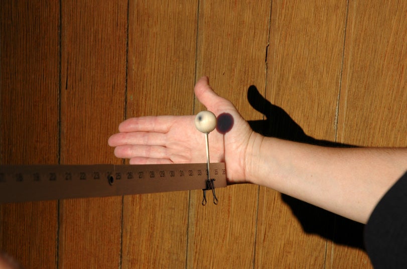 Meter stick with balls modeling a solar eclipse when light is cast